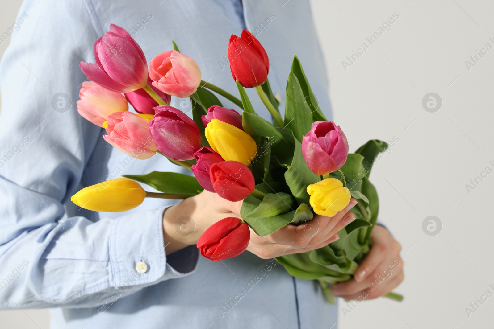 Photo of Woman holding beautiful colorful tulip flowers on white background, closeup