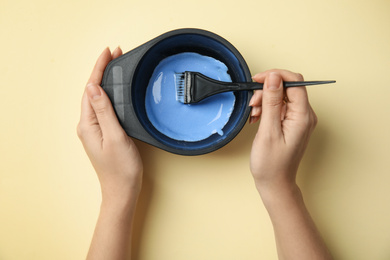 Woman preparing dye for hair coloring on light background, top view