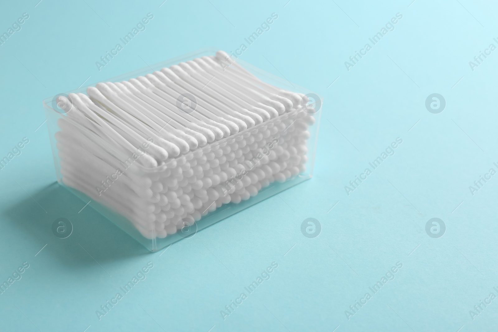 Photo of Plastic container with cotton swabs on color background. Space for text