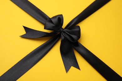 Black satin ribbon with bow on yellow background