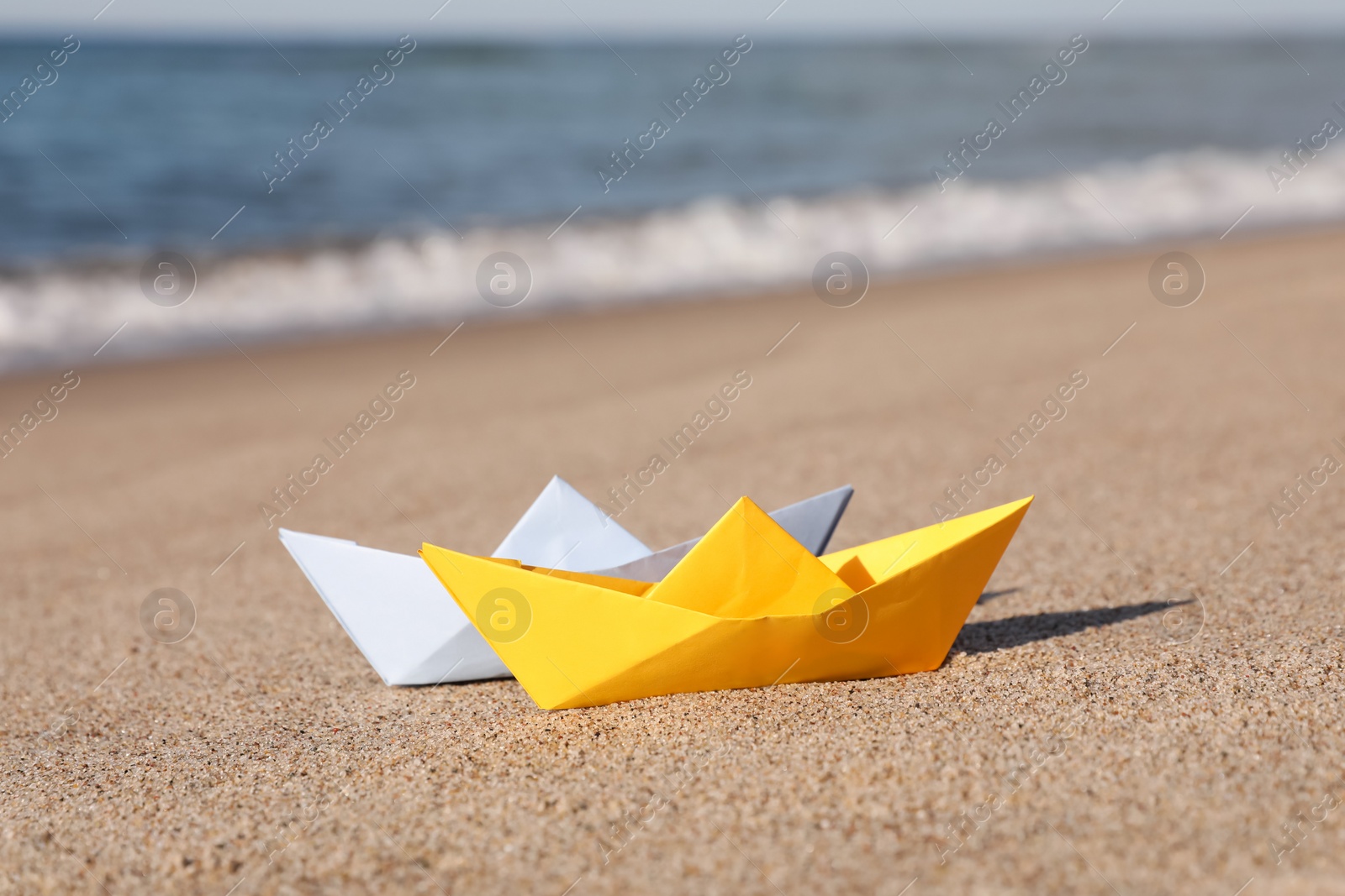 Photo of Color paper boats near sea on sandy beach