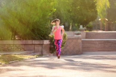 Photo of Young woman running in park on sunny day
