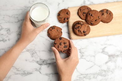 Woman with tasty chocolate chip cookies and milk on light background, closeup