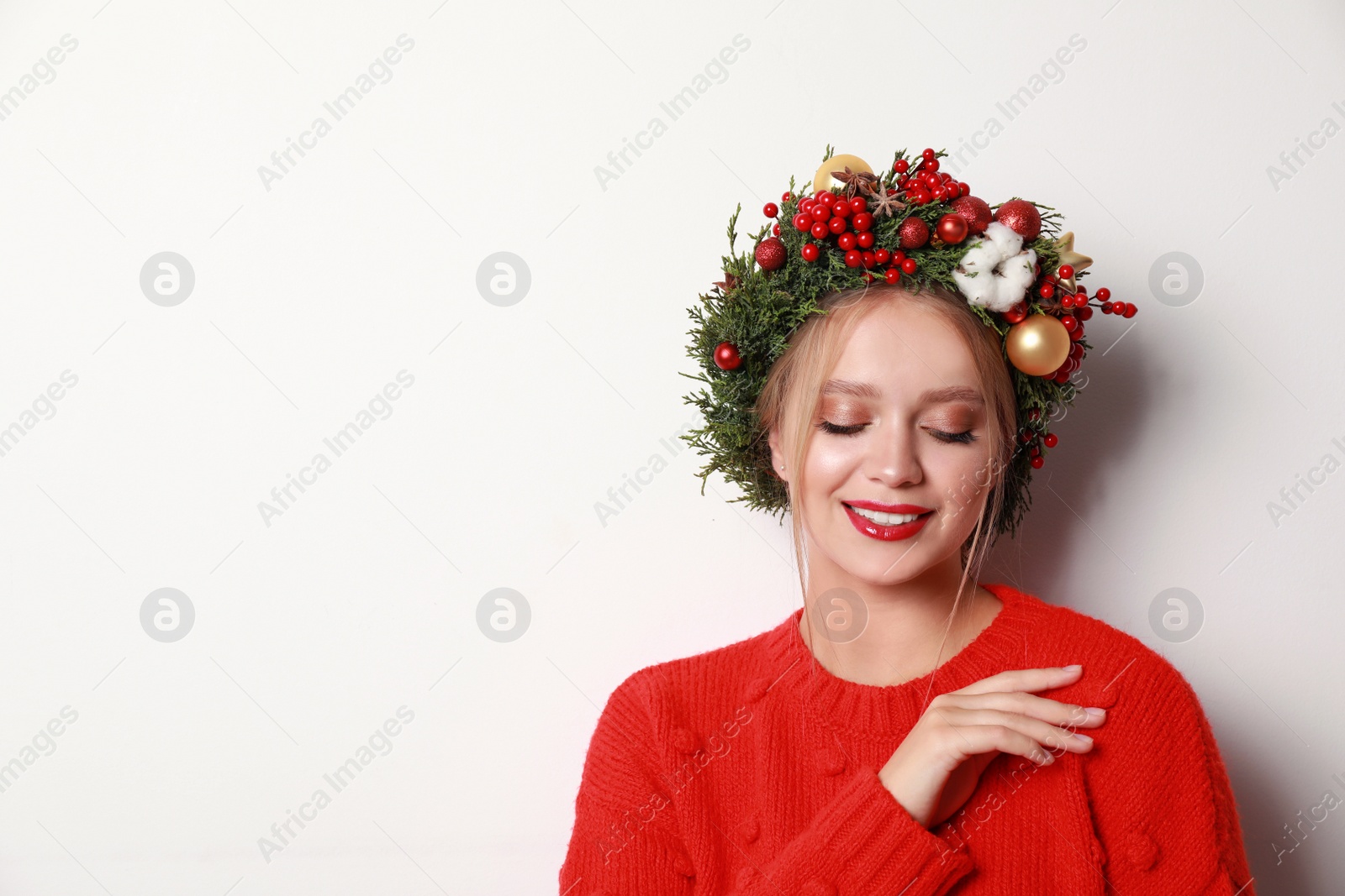 Photo of Beautiful young woman wearing Christmas wreath on white background. Space for text