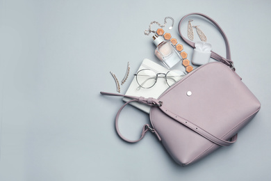 Photo of Stylish woman's bag with accessories on light grey background, flat lay. Space for text
