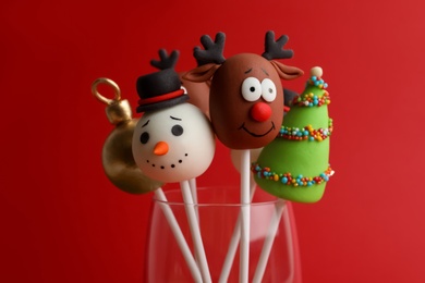 Delicious Christmas themed cake pops on red background, closeup