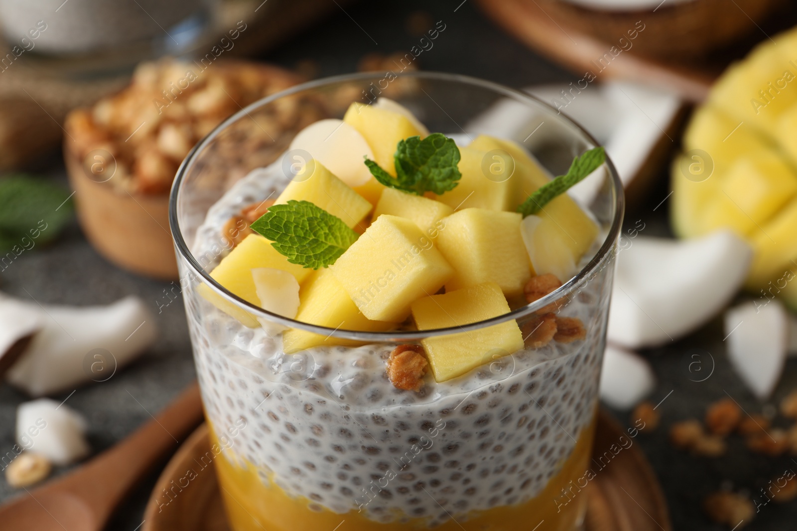 Photo of Delicious chia pudding with mango, mint and granola in glass, closeup