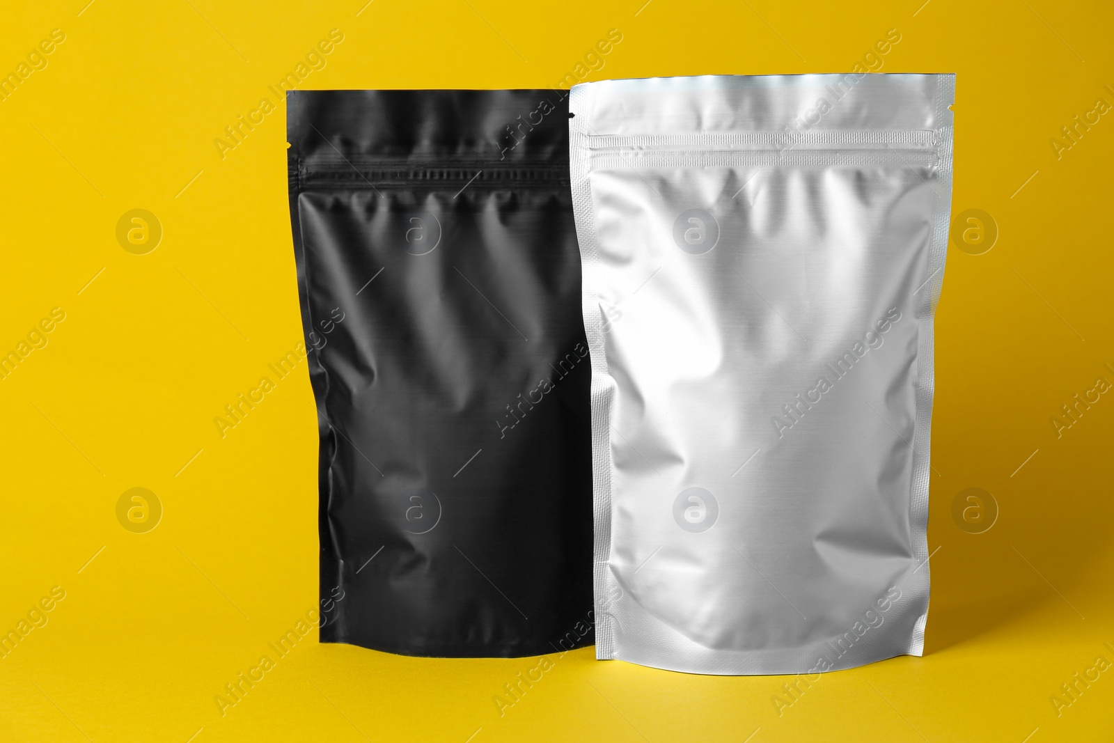 Photo of Different blank foil packages on yellow background