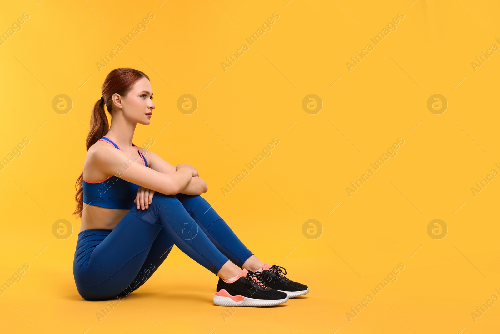 Photo of Young woman wearing sportswear on yellow background, space for text