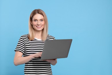 Photo of Happy woman with laptop on light blue background. Space for text