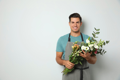 Photo of Florist with beautiful bouquet on light background, space for text