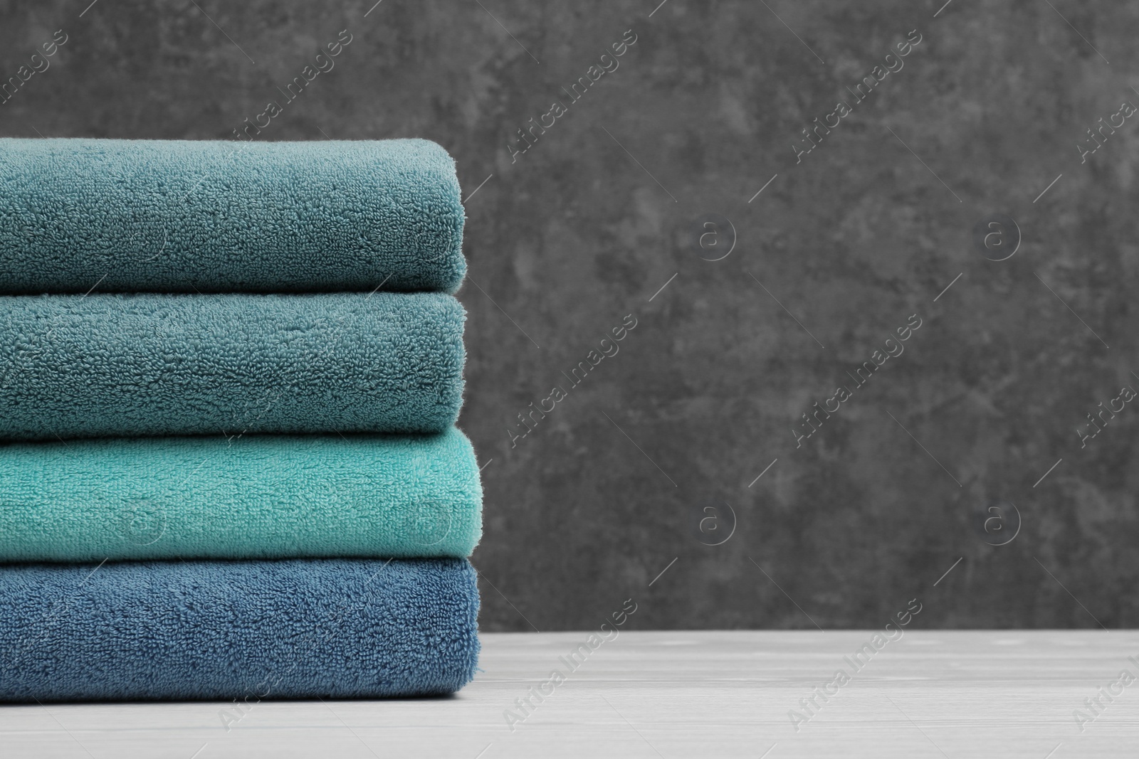 Photo of Stack of soft clean towels on table. Space for text