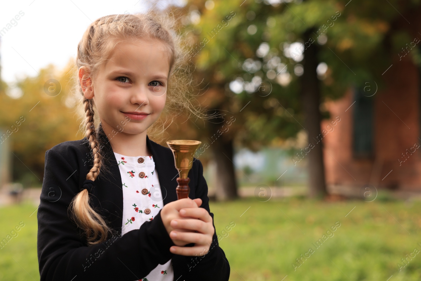 Photo of Pupil with school bell outdoors on sunny day, space for text