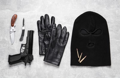 Flat lay composition with balaclava and weapons on light table