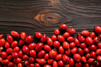 Photo of Fresh ripe rosehip berries on wooden table, flat lay. Space for text