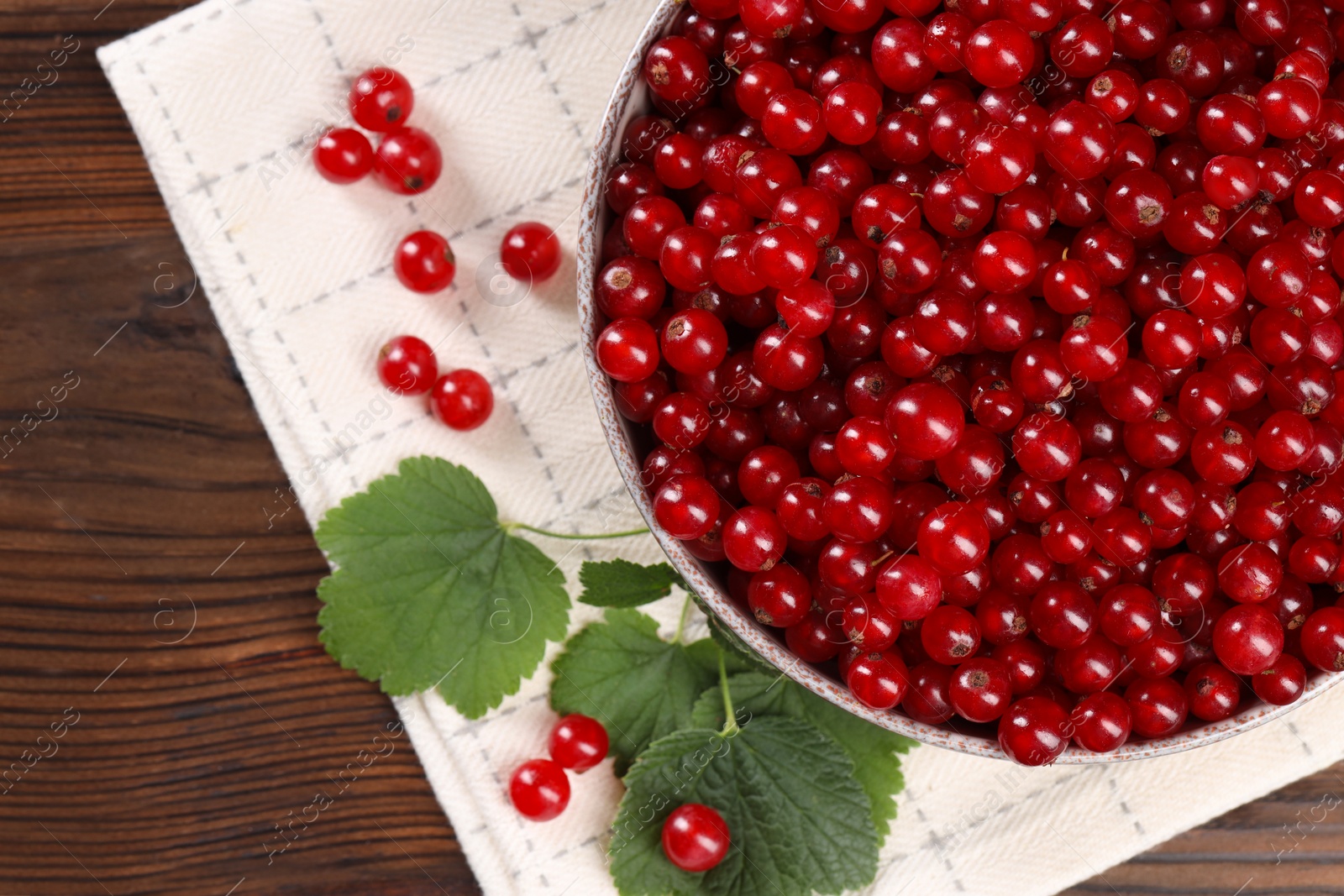 Photo of Ripe red currants and leaves on wooden table, flat lay. Space for text