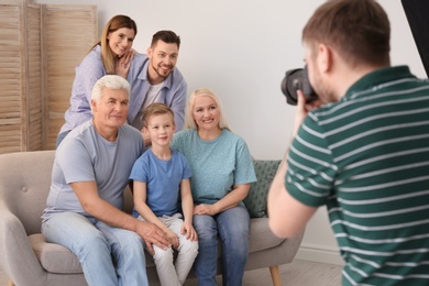 Photo of Professional photographer taking photo of family on sofa in studio