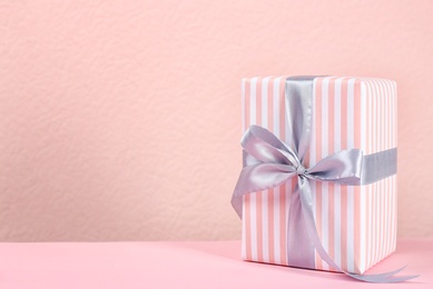 Beautiful gift box on table against color background