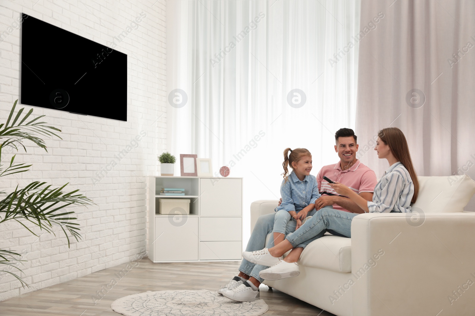 Photo of Happy family watching TV on sofa at home