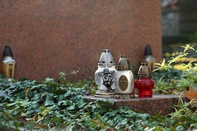 Photo of Grave lanterns and ivy near tombstone in cemetery