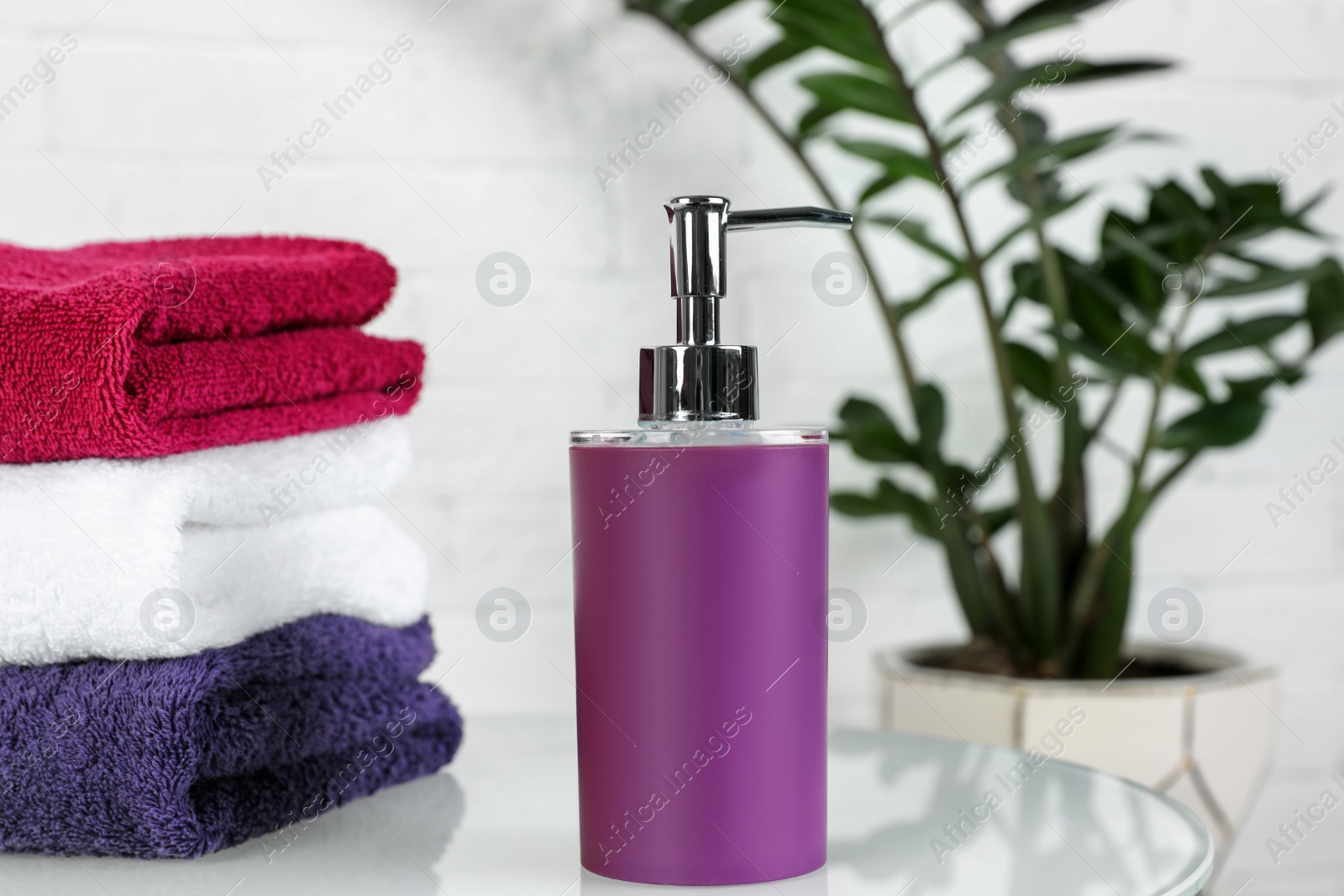 Photo of Bottle of liquid soap and towels on table