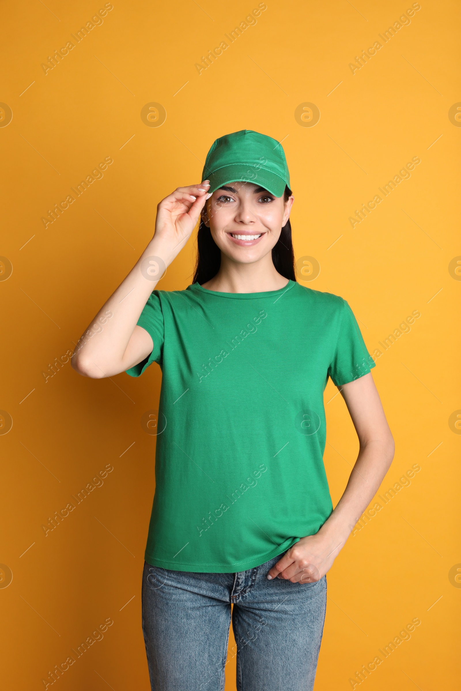 Photo of Young happy woman in green cap and tshirt on yellow background. Mockup for design