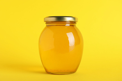 Jar of organic honey on yellow background