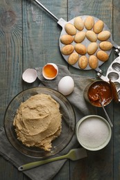 Photo of Freshly baked homemade walnut shaped cookies, dough and ingredients on wooden table, flat lay