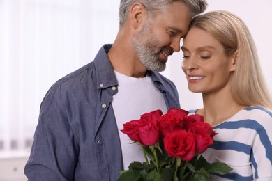 Photo of Happy affectionate couple with bouquet of roses at home. Romantic date