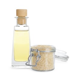 Photo of Glass bottle of fresh sesame oil and jar with seeds isolated on white