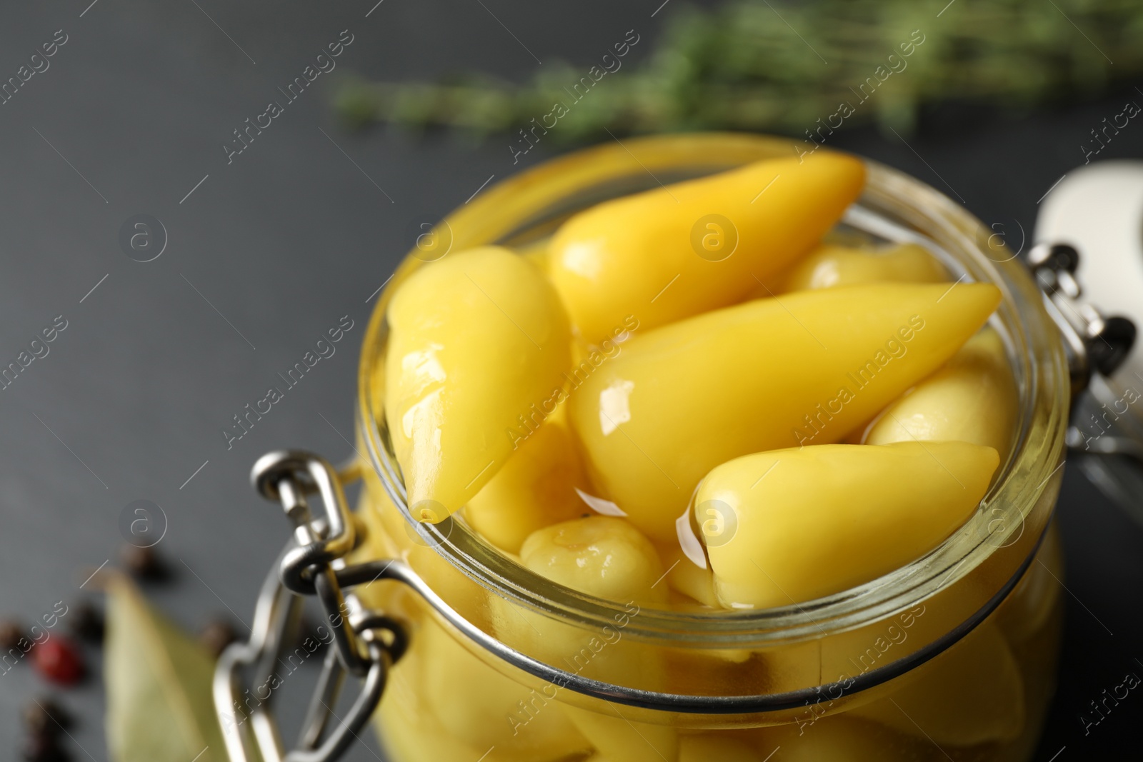 Photo of Glass jar with pickled peppers on black table, closeup