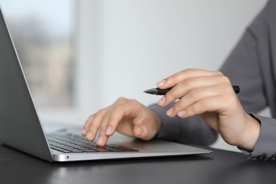 Woman with pen working on laptop, closeup. Electronic document management