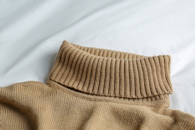 Stylish knitted sweater on white fabric, closeup