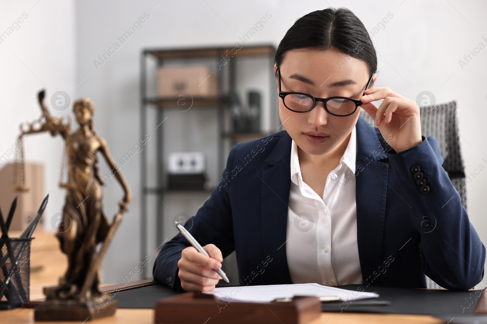 Photo of Notary signing document at table in office