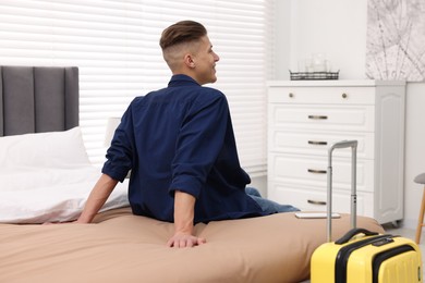 Photo of Smiling guest relaxing on bed in stylish hotel room