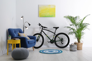 Modern bicycle and comfortable armchair in stylish living room interior