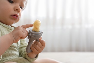 Photo of Cute baby girl with nibbler at home. Space for text