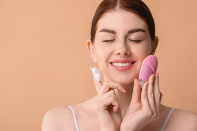 Washing face. Young woman with brush and cleansing foam on beige background, space for text