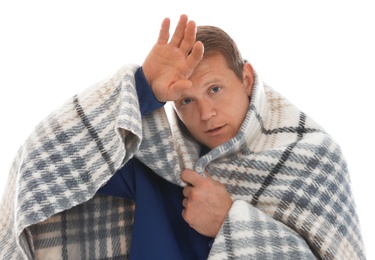 Man wrapped in warm blanket suffering from cold on white background