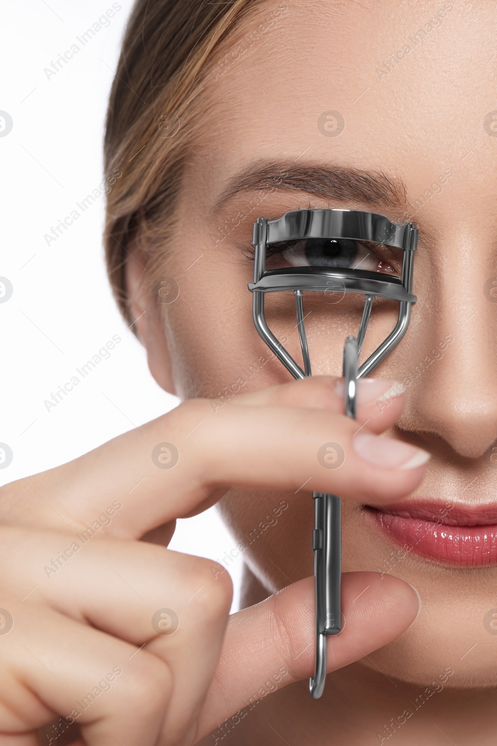 Photo of Young woman using eyelash curler on white background, closeup