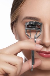 Young woman using eyelash curler on white background, closeup