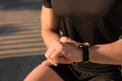 Photo of Man checking pulse after training outdoors, closeup