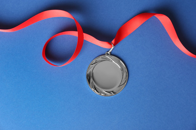 Photo of Silver medal on blue background, top view. Space for design