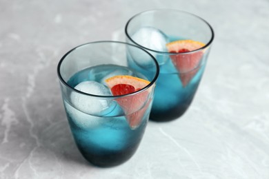 Delicious cocktails with grapefruit and ice balls on grey table