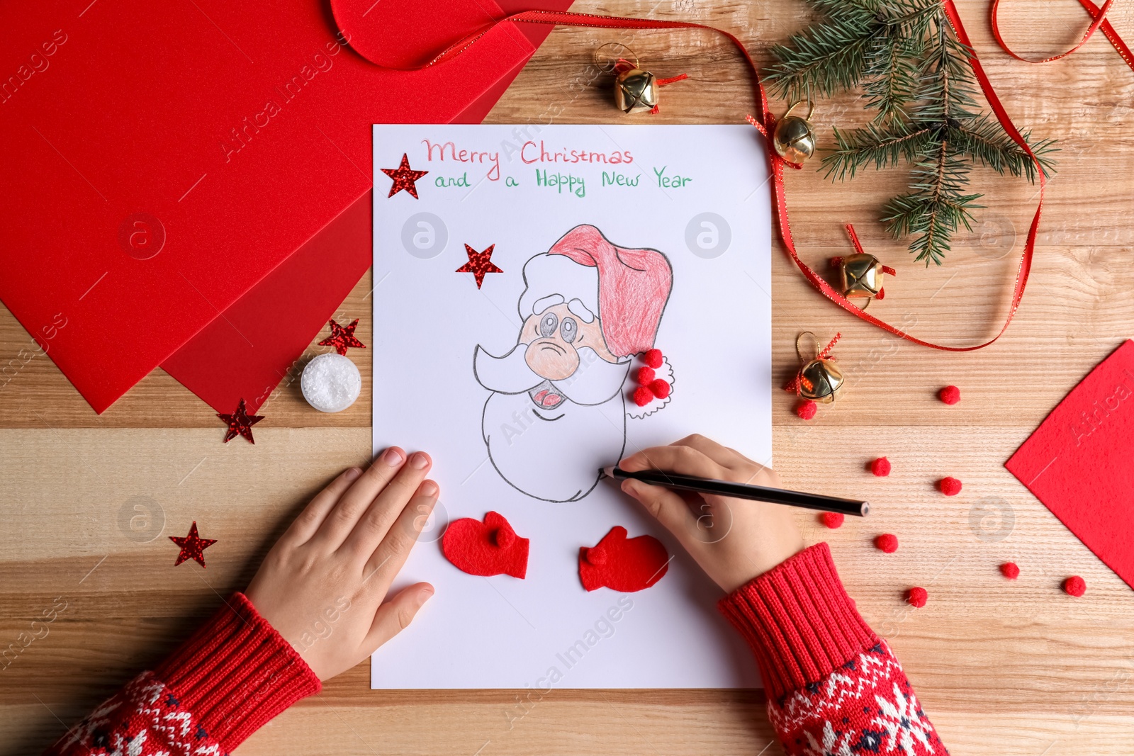 Photo of Little child making Christmas card at wooden table, top view