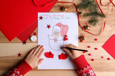 Little child making Christmas card at wooden table, top view