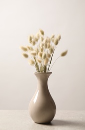 Dried flowers in vase on table against light background