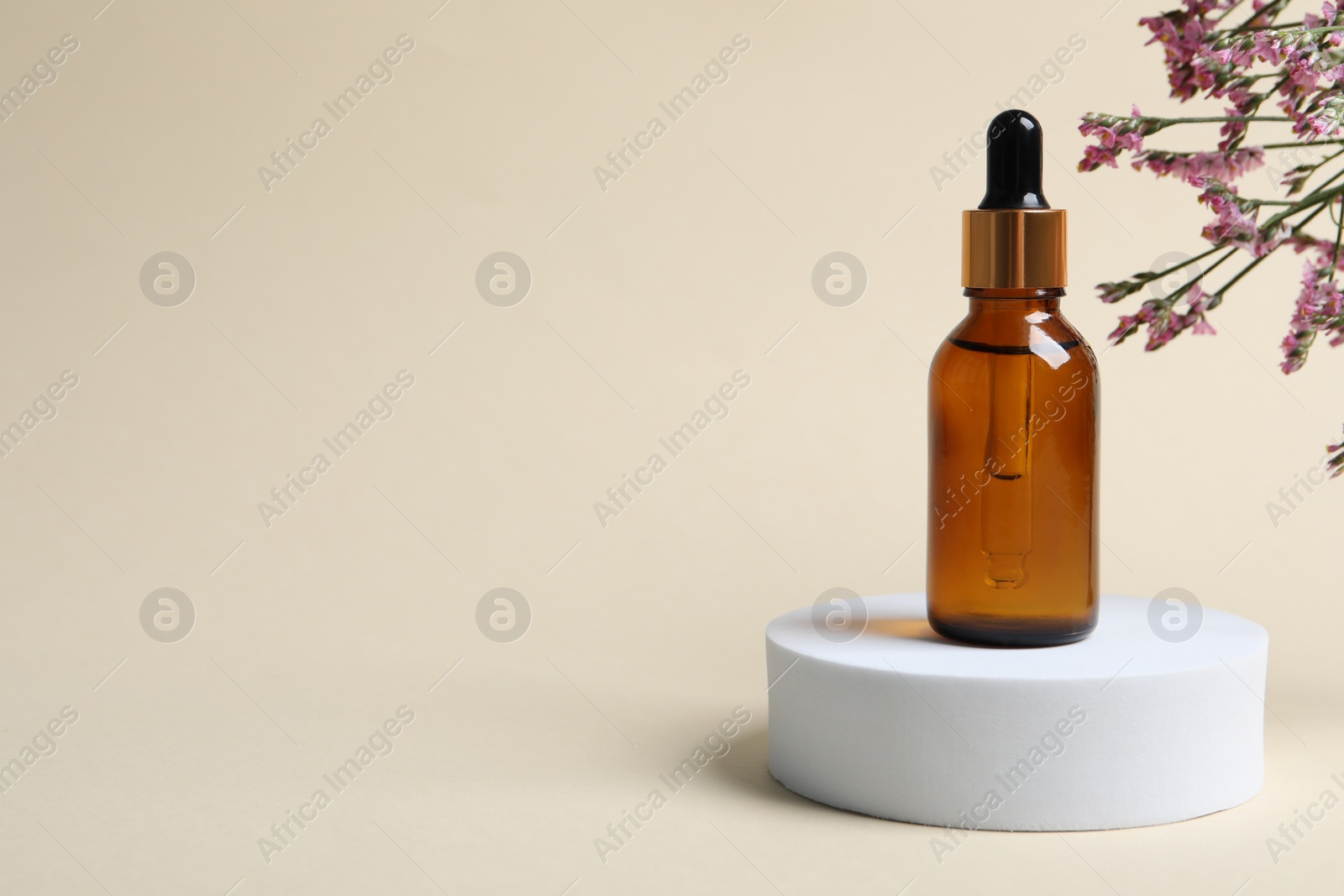 Photo of Bottle of cosmetic oil and flowers on beige background. Space for text