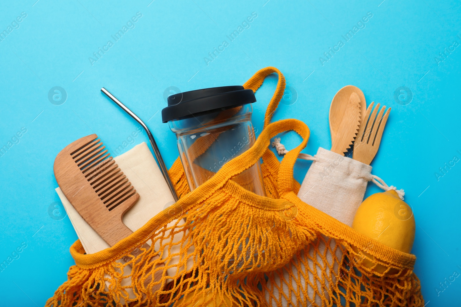 Photo of Bag with eco friendly products on turquoise background, top view