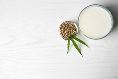 Photo of Glass of hemp milk and space for text on white wooden background, top view